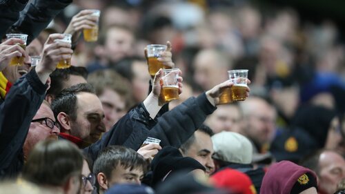 Personas bebiendo cerveza en un estadio de fútbol