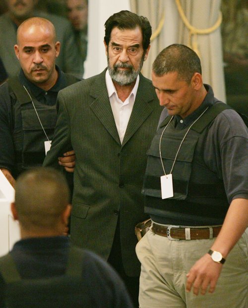Saddam Hussein junto a dos policías.